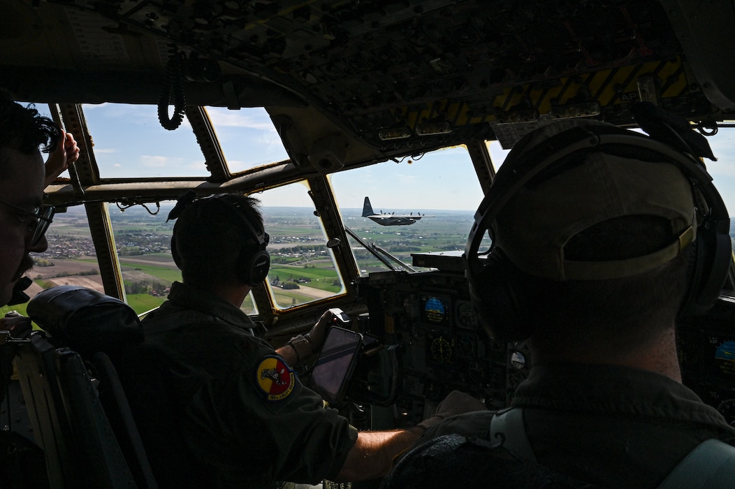 U.S. Air Force Maj. Edwin Fattman, left, and 1st Lt. David Kocher, 180th Airlift Squadron pilots, look over at a C-130H Hercules aircraft from the 139th Airlift Wing, during Hussar Saber 26-1.