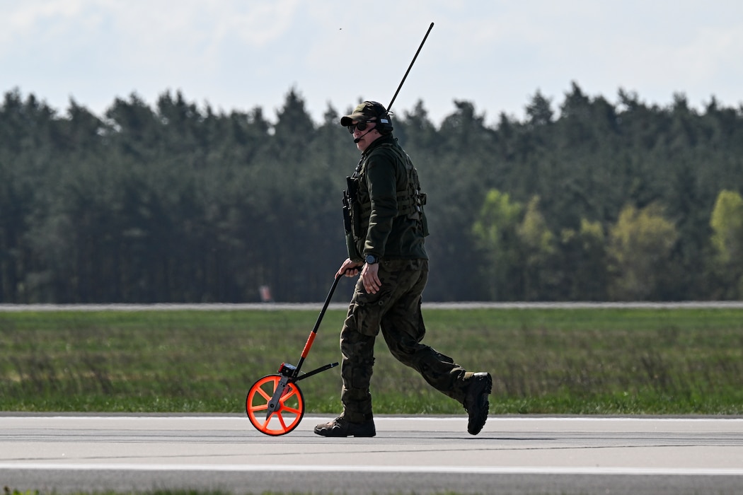 A Polish forces member assigned to the 33rd Airlift Base uses a measuring wheel to calculate the landing zone distance on the flight line during Rodeo Day in support of Hussar Saber 26-1.