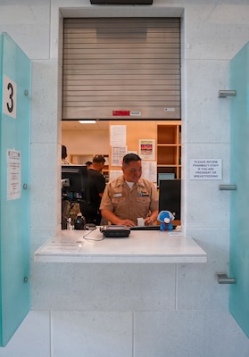 Hospital Corpsman 1st Class Steven R. Deguzman, a pharmacy technician, verifies patient information and processes prescriptions at one of U.S. Naval Hospital Guam's pharmacy windows. As a pharmacy technician, Deguzman screens and enters medication orders to ensure accuracy and compliance with prescription criteria, directly supporting patient safety and reliable pharmaceutical care across the command. Deguzman is a member of USNH Guam's pharmacy team, which was recognized as the U.S. Navy Pharmacy Team of the Year for fiscal year 2025. The award was announced during a ceremony at the Joint Federal Pharmacy Seminar Nov. 1, 2025 and recognizes the team’s outstanding contributions to operational readiness, patient care, and process improvement, solidifying their role as a cornerstone of pharmaceutical support in the Indo-Pacific Command (INDOPACOM) area of responsibility.