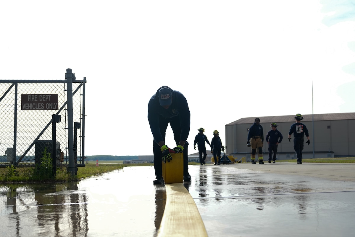 A firefighter rolls up a fire hose