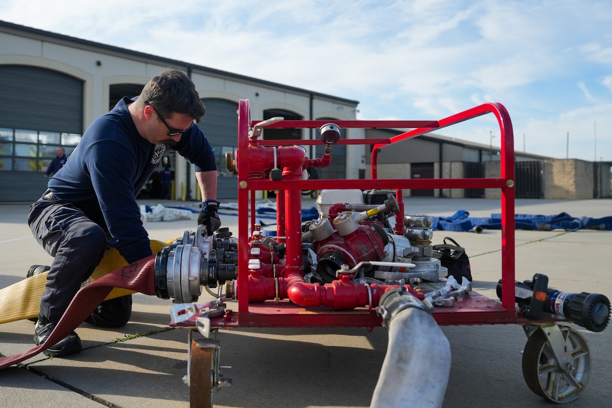 A firefighter tightens a fire hose coupling onto a fire hose tester