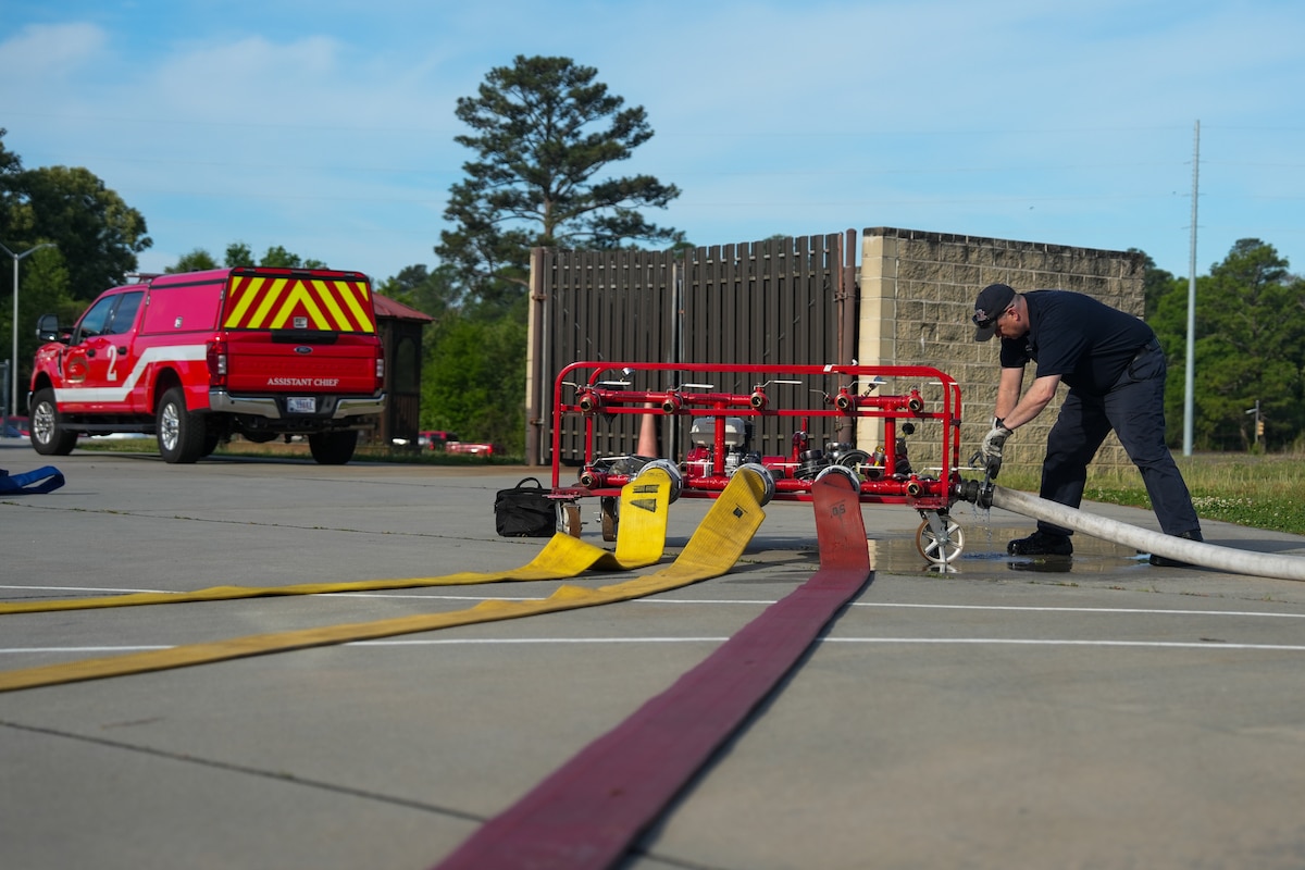 A firefighter tightens a fire hose's coupling onto a fire hose tester