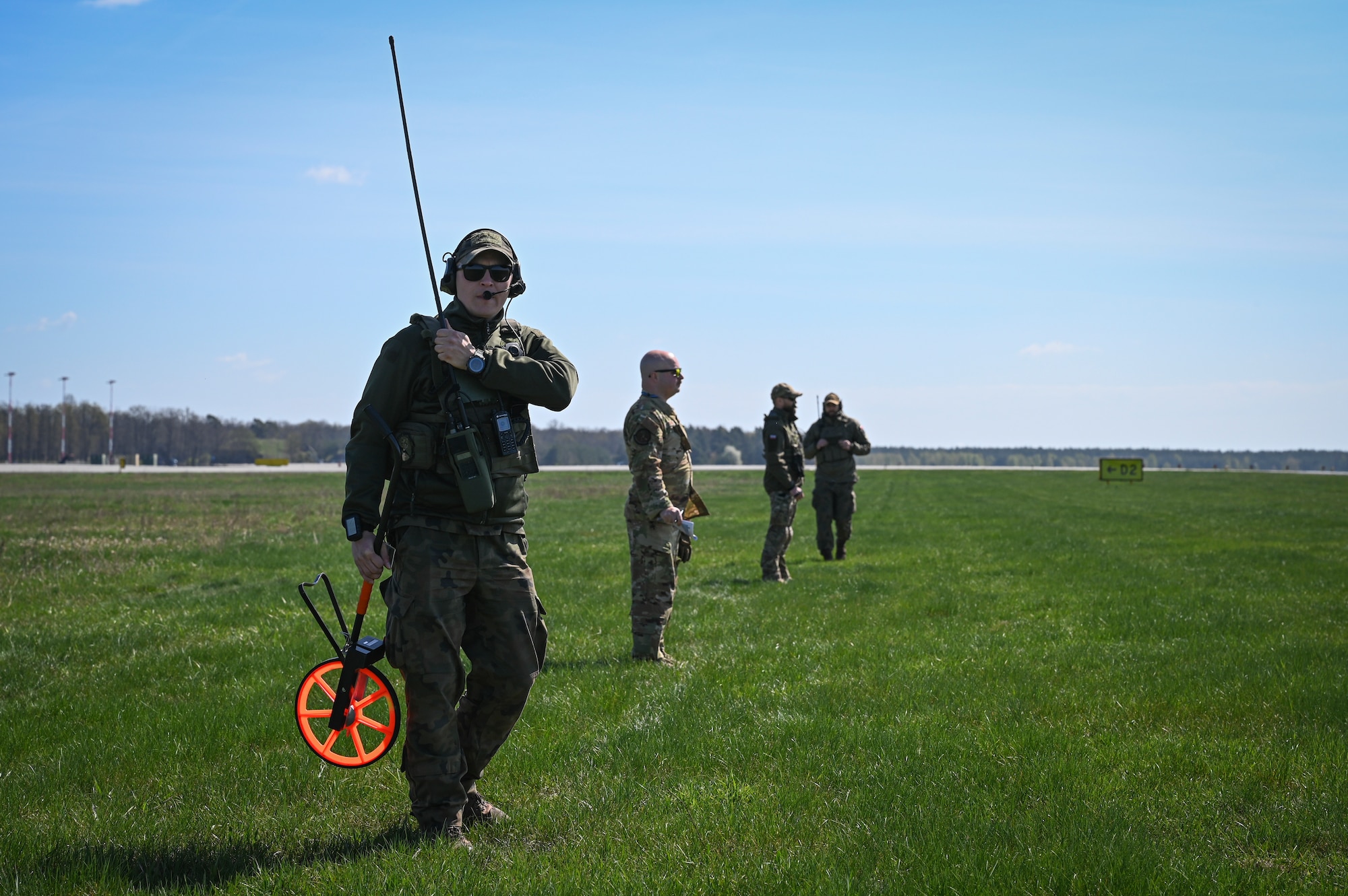 A U.S. Airman assigned to the 139th Airlift Wing and Polish Allies assigned to the 33rd Airlift Base prepare to mark a landing of a C-130H Hercules aircraft from the 139th Airlift Wing, during Rodeo Day in support of Hussar Saber 26-1.