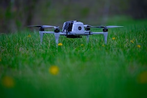 A military drone sits on a grassy field.