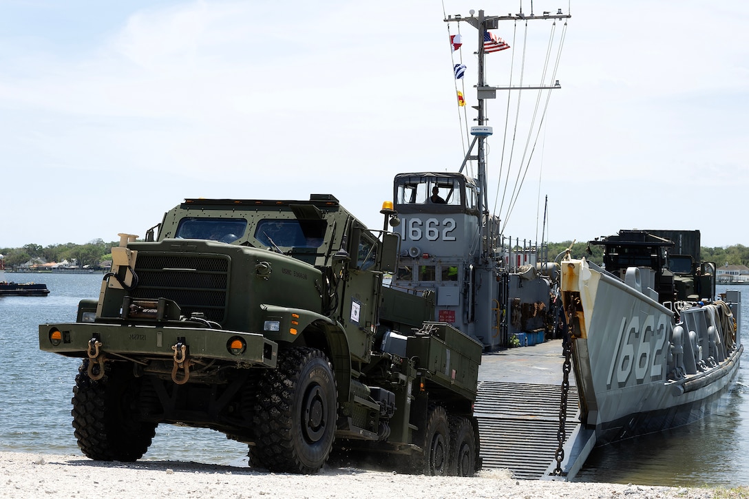 An up-armored MK36 Medium Tactical Vehicle Replacement wrecker rolls off a landing craft utility May 5, 2026, at Marine Corps Support Facility Blount Island in Jacksonville, Florida, during ship-to-shore operations supporting the 22nd Marine Expeditionary Unit (Special Operations Capable). The movement enabled rapid equipment transfer to sustain operations in the U.S. Southern Command area of responsibility. (U.S. Marine Corps photo by Dustin Senger)