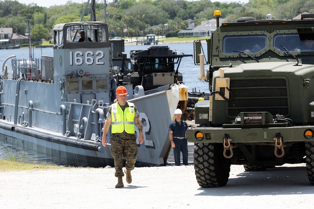 U.S. Marine Corps Master Gunnery Sgt. Garrett Mitchell, operations chief at Blount Island Command, assists as an up-armored MK36 Medium Tactical Vehicle Replacement wrecker rolls off a landing craft utility May 5, 2026, at Marine Corps Support Facility Blount Island in Jacksonville, Florida, during ship-to-shore operations supporting the 22nd Marine Expeditionary Unit (Special Operations Capable). The movement enabled rapid equipment transfer to sustain operations in the U.S. Southern Command area of responsibility. (U.S. Marine Corps photo by Dustin Senger)