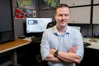 Adam Moses, U.S. Naval Research Laboratory (NRL) computer scientist, poses for a photo with the Contaminant Transport (CT) Analyst system in Washington, D.C., April 24, 2026. CT-Analyst is an NRL developed tool that models airborne hazards in real time for faster operational access and on-demand access to predictions. (U.S. Navy photo by Sarah Peterson)
