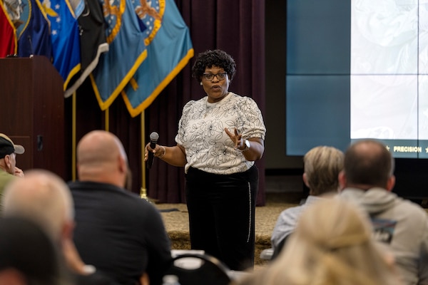 A woman speaks to a room of people.
