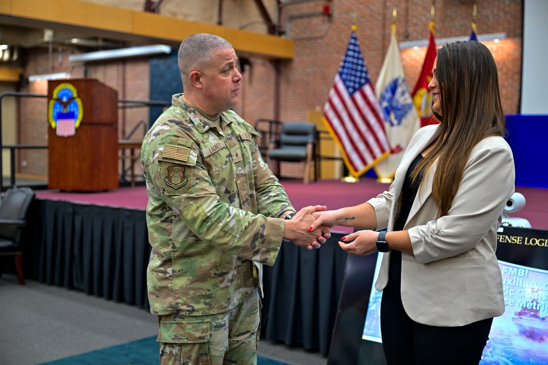 A military officer shakes the hand of a female employee.