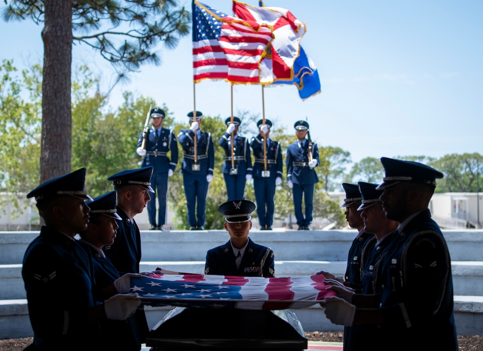 Pallbearers hold the flag above a casket during an Honor Guard graduation ceremony
