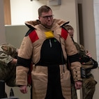 A Community Leadership Institute (CLI) member tries on an explosive ordnance disposal (EOD) bomb suit at Minot Air Force Base, North Dakota, April 30, 2026. The CLI members were given an opportunity to learn about the EOD mission while on a guided tour around base. (U.S. Air Force photo by Airman Ben Selchow)