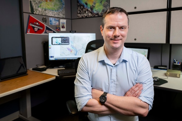 Adam Moses, U.S. Naval Research Laboratory (NRL) computer scientist, poses for a photo with the Contaminant Transport (CT) Analyst system in Washington, D.C., April 24, 2026. CT-Analyst is an NRL developed tool that models airborne hazards in real time for faster operational access and on-demand access to predictions. (U.S. Navy photo by Sarah Peterson)