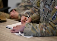 A service member takes notes during a meeting.