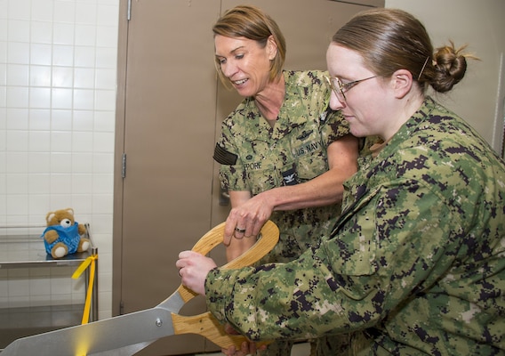 A Cut Above… Capt. Karla Lepore, Naval Hospital Bremerton director and Navy Medicine Readiness Training Command Bremerton commanding officer is assisted by Hospital Corpsman 2nd Class Megan Calderon, Main Operating Room surgical technologist with a ribbon-cutting ceremony in the Sterile Processing Department to formally proclaim restoration of vital cart washer ability after a two-year outage of such a critical service. No more time-consuming manual washing, cleaning, and sanitizing. “Super excited with this,” exclaimed Calderon. “I love it.” (Official Navy photo by Mass Communication Specialist 2nd Class Jennifer Benedict, NHB/NMRTC Bremerton public affairs)