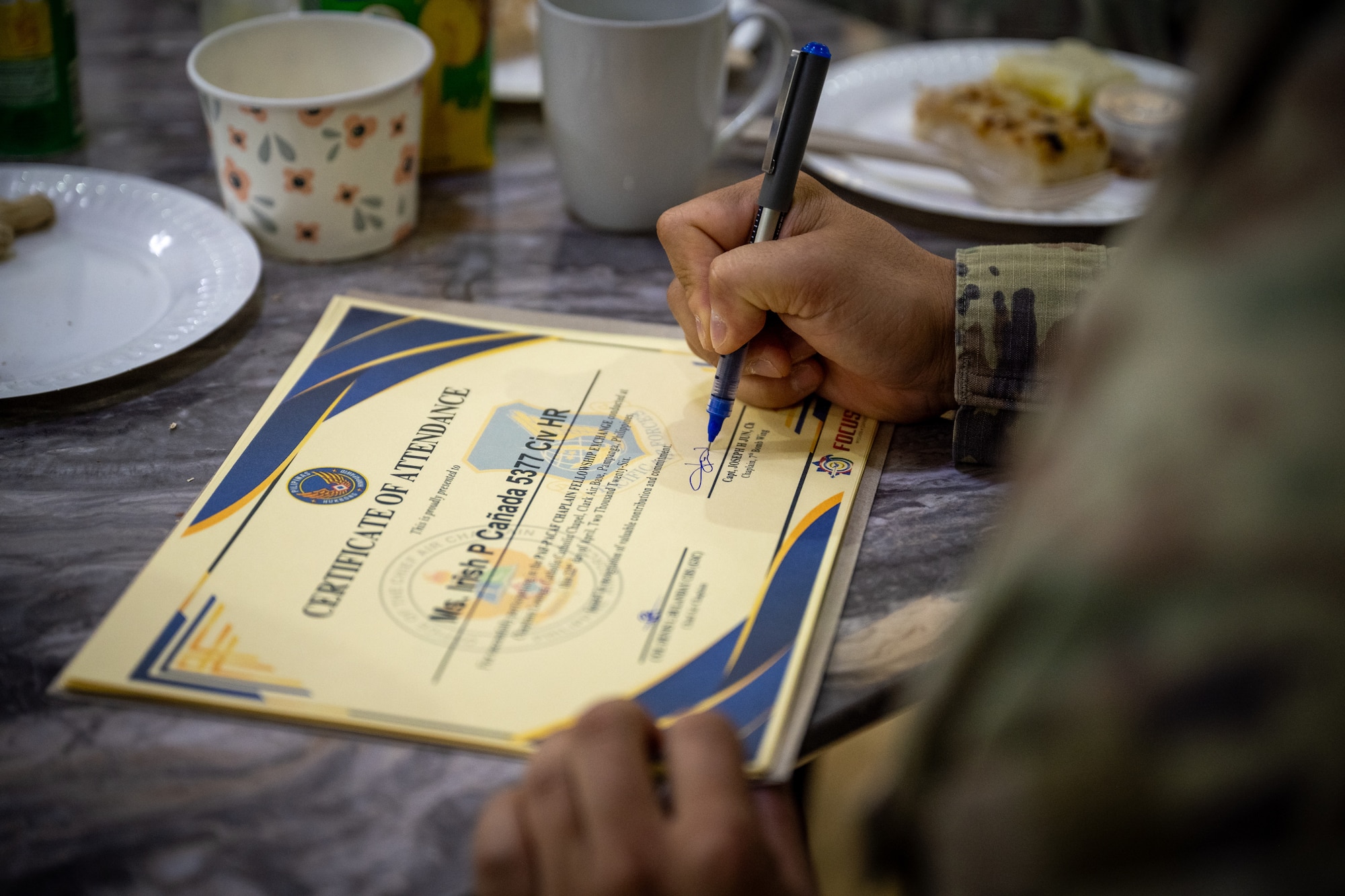 U.S. Air Force Capt. Joseph Jun, 21st Air Expeditionary Wing chaplain, signs a certificate of participation during a chaplain fellowship exchange at Clark Air Base, Philippines, April 22, 2026. The fellowship exchange gave Jun and the Philippine Air Force chaplain corps an opportunity to plan future training events to equip Airmen with resiliency and spiritual fitness. (U.S. Air Force photo by Airman 1st Class Adrien Tran)