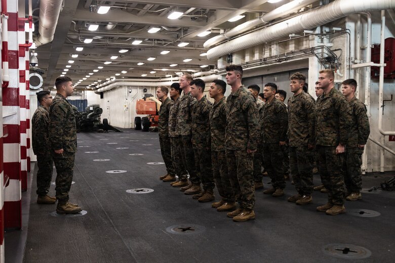 U.S. Marines with Lima Company, Battalion Landing Team 3/5, 11th Marine Expeditionary Unit, stand at the position of attention in the well deck of San Antonio-class amphibious transport dock ship USS Portland (LPD 27), during a promotion ceremony in the Pacific Ocean, Dec. 7, 2025. The 11th MEU is currently underway aboard the Boxer Amphibious Ready Group in the U.S. 3rd Fleet area of operations conducting integrated training that enhances lethality and warfighting readiness. (U.S. Marine Corps photo by Lance Cpl. Luke Rodriguez)