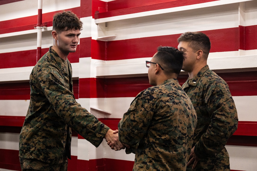 U.S. Marine Corps Lance Cpl. Joseph Newman, left, a rifleman with Lima Company, Battalion Landing Team 3/5, 11th Marine Expeditionary Unit, shakes hands with Marines during a promotion ceremony in the well deck of San Antonio-class amphibious transport dock ship USS Portland (LPD 27), in the Pacific Ocean, Dec. 7, 2025. The 11th MEU is currently underway aboard the Boxer Amphibious Ready Group in the U.S. 3rd Fleet area of operations conducting integrated training that enhances lethality and warfighting readiness. (U.S. Marine Corps photo by Lance Cpl. Luke Rodriguez)