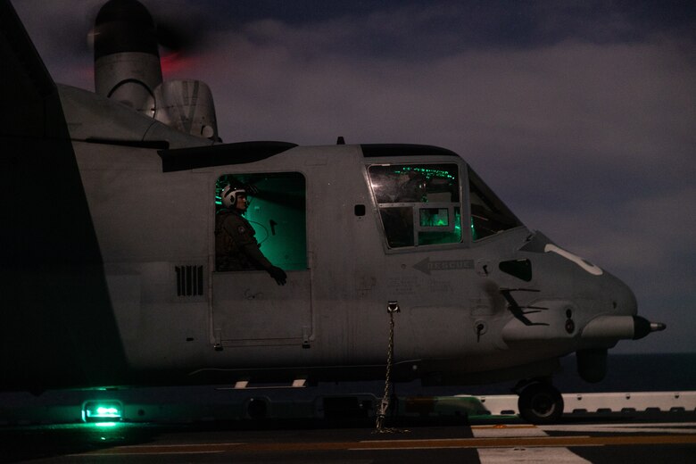 A U.S. Marine Corps crew chief with Marine Medium Tiltrotor Squadron (VMM) 163 (Reinforced), 11th Marine Expeditionary Unit, observes night deck landing qualifications from a MV-22B Osprey aboard Wasp-class amphibious assault ship USS Boxer (LHD 4) in the Pacific Ocean, Dec. 3, 2025. The 11th MEU is currently underway aboard the Boxer Amphibious Ready Group in the U.S. 3rd Fleet area of operations conducting integrated training that enhances lethality and warfighting readiness. (U.S. Marine Corps photo by Cpl. Oliver Nisbet)