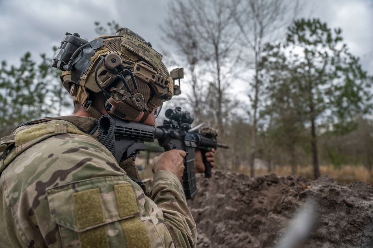 A U.S. military member fires a rifle. Shells are seen leaving the rifle in the photo