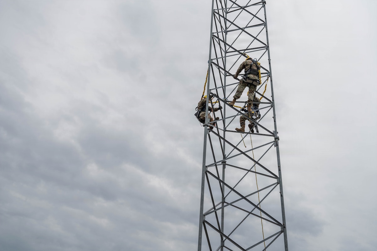 Airmen climb a tower.