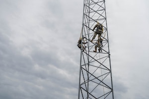 Airmen climb a tower.