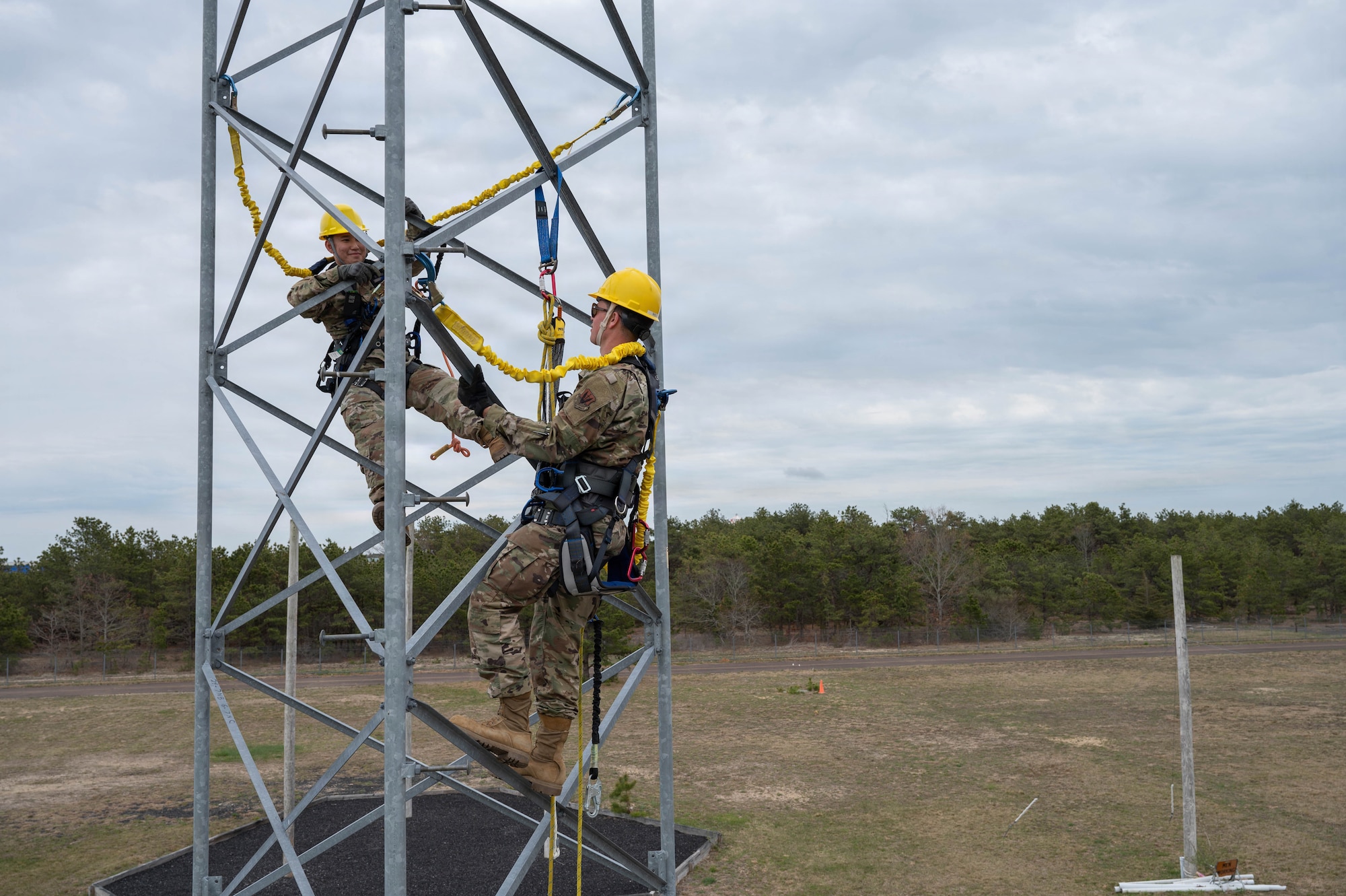 Airmen climb a tower.