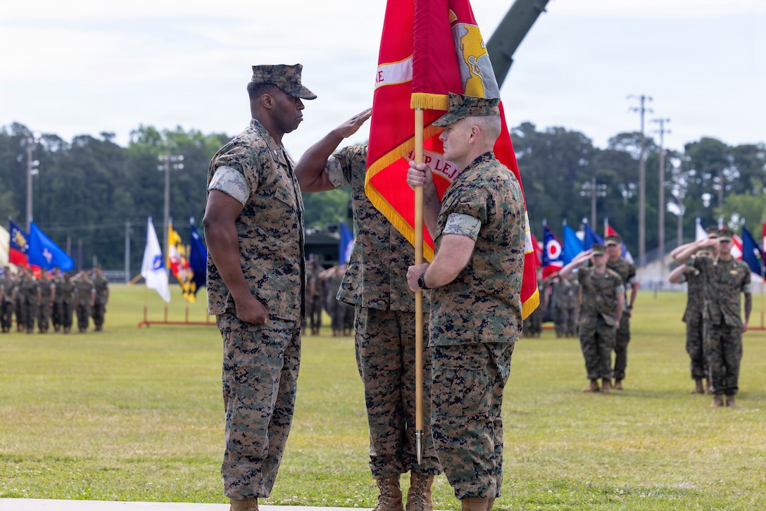 U.S. Marine Corps Col. Gregory B. Pace, left, the incoming commander, Marine Corps Installations East-Marine Corps Base Camp Lejeune, is presented the unit colors by U.S. Marine Corps Brig. Gen. Ralph J. Rizzo, Jr., right, the outgoing commanding general, MCIEAST-MCB Camp Lejeune, during a relinquishment of command ceremony at W.P.T. Hill Field on MCB Camp Lejeune, North Carolina, May 8, 2026. During the ceremony, Rizzo relinquished command of MCIEAST to Pace. Pace is a native of Tuskegee, Alabama, and Rizzo is a native of Charlestown, Massachusetts. (U.S. Marine Corps photo by Lance Cpl. Erica S. Padgett)