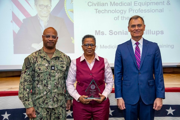 260504-N-KC192-1052 PORTSMOUTH, Va. (May 4, 2026)  Sonia Billups, with Navy Medicine Operational Training Command, is presented the Civilian Medical Equipment and Technology Professional of the Year Award by Dr. Michael McGinnis, Bureau of Medicine and Surgery (BUMED) executive director, during the 2026 Medical Logistics Symposium held on board Naval Medical Center Portsmouth, May 4, 2026. Billups was recognized for advancing property management and technical support systems, strengthening the accountability and readiness of equipment used in expeditionary operations. The Navy Medicine Logistics Symposium aims to maintain a common operating picture and update the Medical Logistics community regarding the fiscal year 2026 Navy Medicine Campaign Order and the Navy MEDLOG goal to build a logistics system that delivers ready operational units to support the Naval Strategy. (U.S. Navy photo by Mass Communication Specialist Second Class Levi Decker)