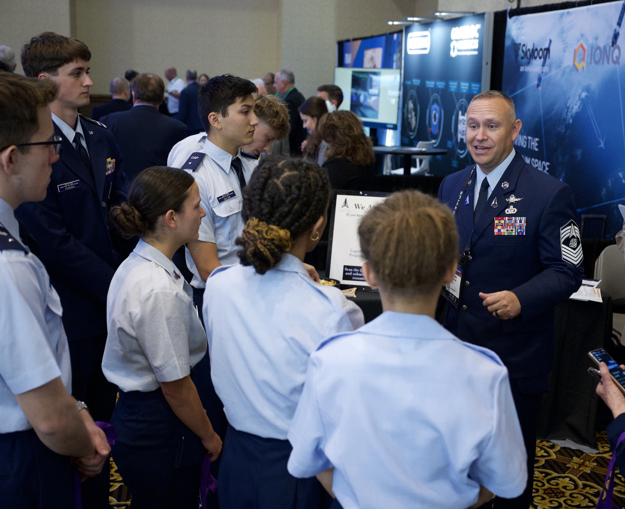 Chief Master Sgt. Charles Apodaca, Senior Enlisted Leader, Space Systems Command (SSC) Space Launch Delta 45, converses with high school STEM students on April 16, 2026 during the 41st Space Symposium in Colorado Springs, Colorado.  SSC STEM outreach is designed to foster early interest in science, technology, engineering, and math, helping prepare future generations to support national defense and space operations. (USSF photo by Sarah McNulty)