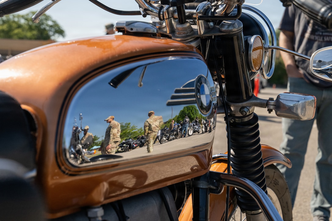 A reflection off a motorcycle showing people and other motorcycles.