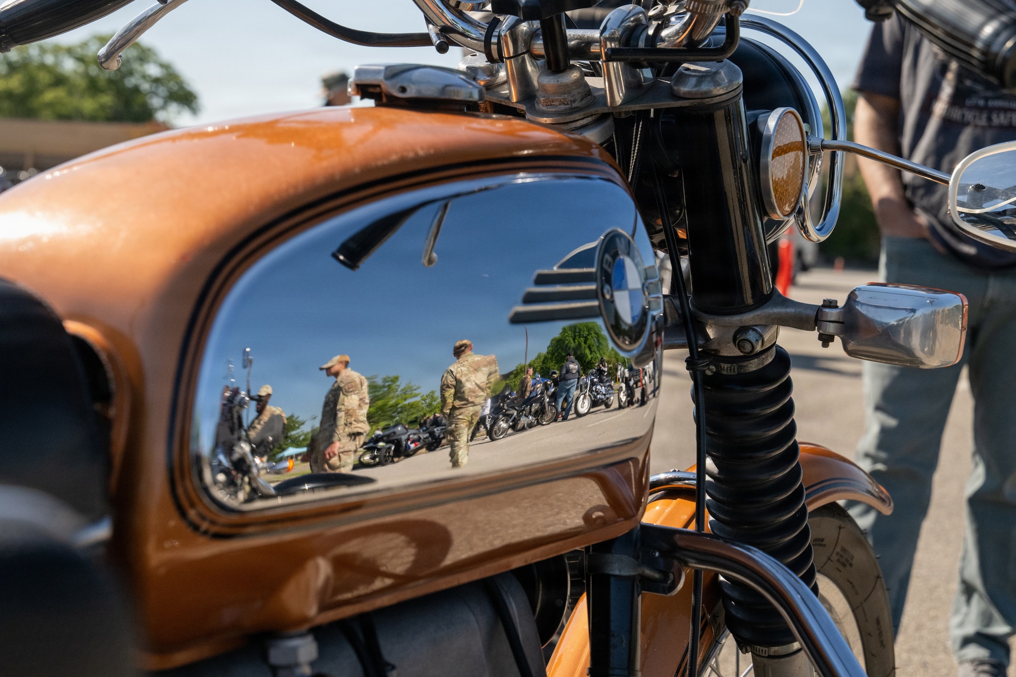 A reflection off a motorcycle showing people and other motorcycles.