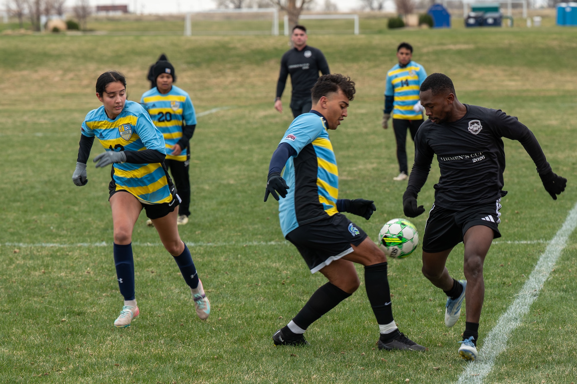 Nuke FC player advances down the field against University of Providence team members in a soccer game.