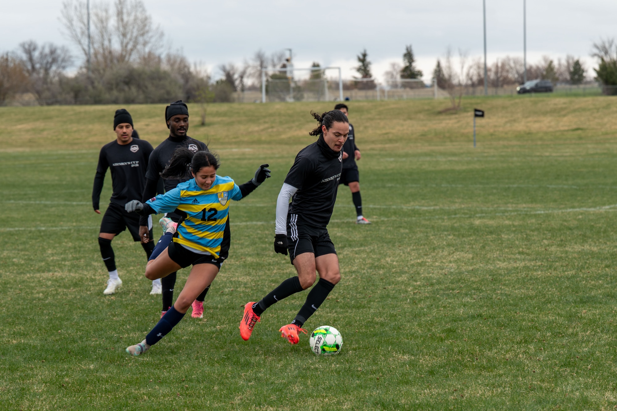 Nuke FC player dribbles soccer ball away from University of Providence player during soccer match.