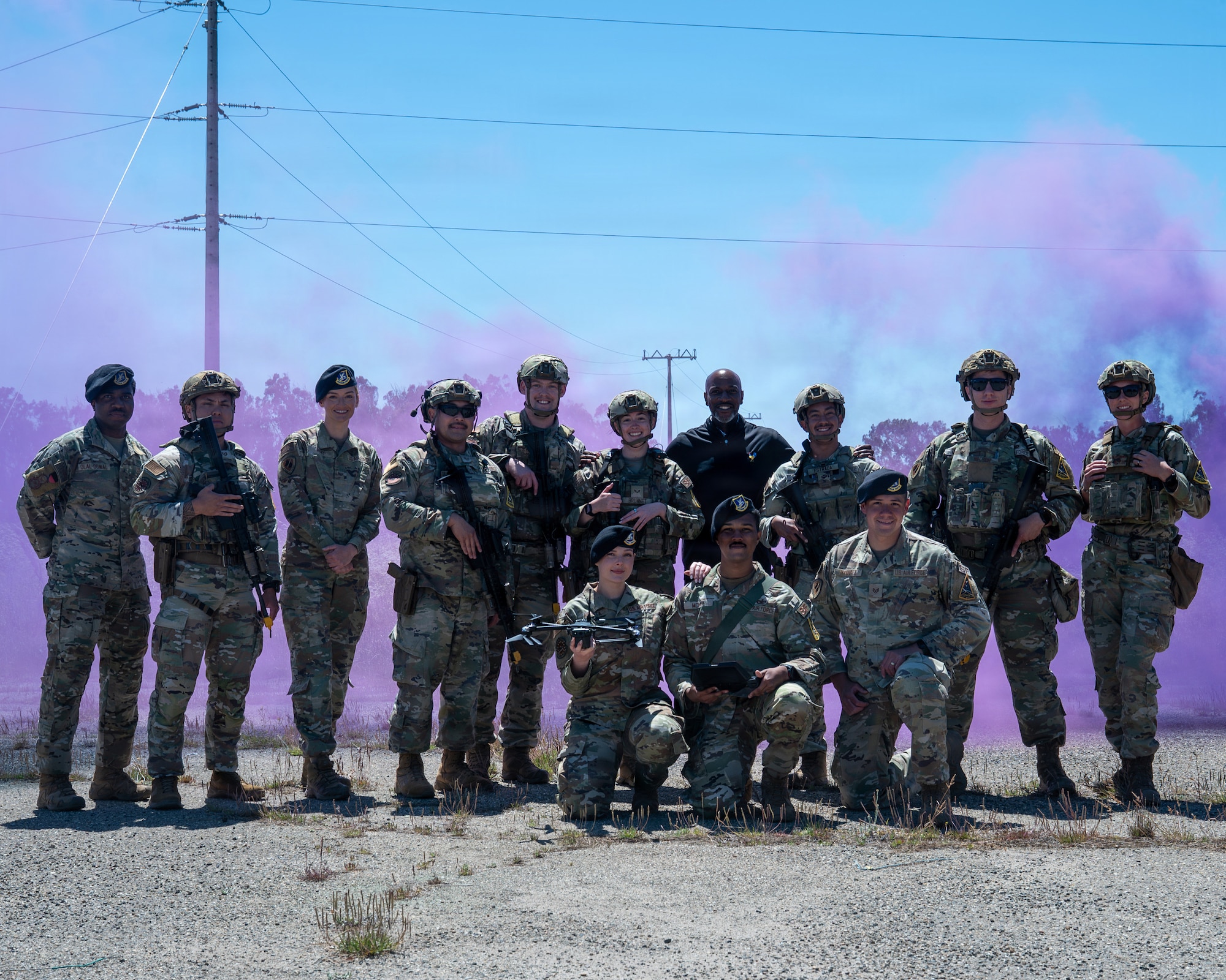 People stand for a group photo. There is purple smoke in the background.