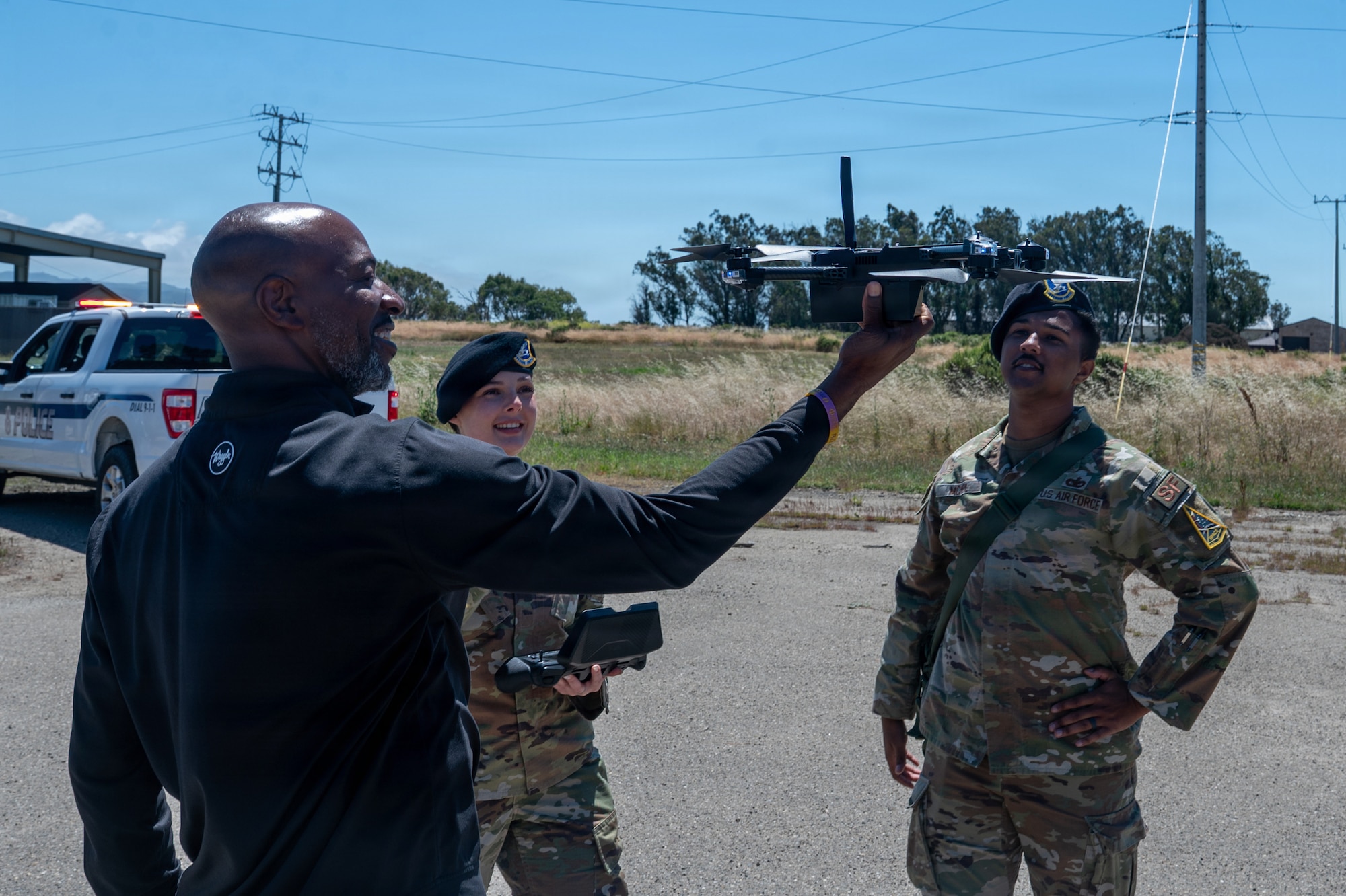 Kaleth O. Wright holds a drone in front of two military members.