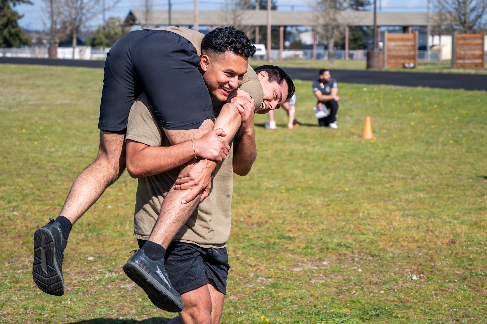 U.S. Air Force Senior Airman Manuel Santiago, 4th Airlift Squadron loadmaster, carries Senior Airman Anthony Mendoza, 5th Air Support Operations Squadron tactical air control party strike journeyman, during the Julius A. Kolb Airman Leadership School Commandant’s Crucible at Joint Base Lewis-McChord, Washington, April 7, 2026.