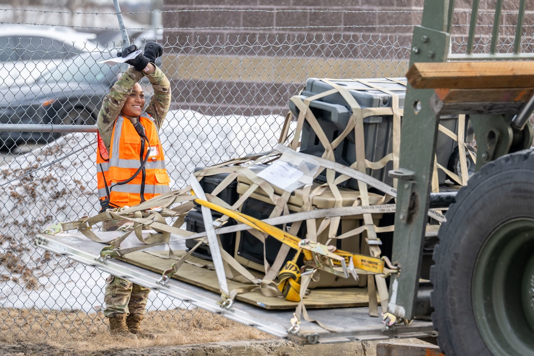 Airman 1st Class Aiyana Erickson, 354th Logistics Readiness Squadron cargo supply marshal, signals to a forklift driver moving supplies