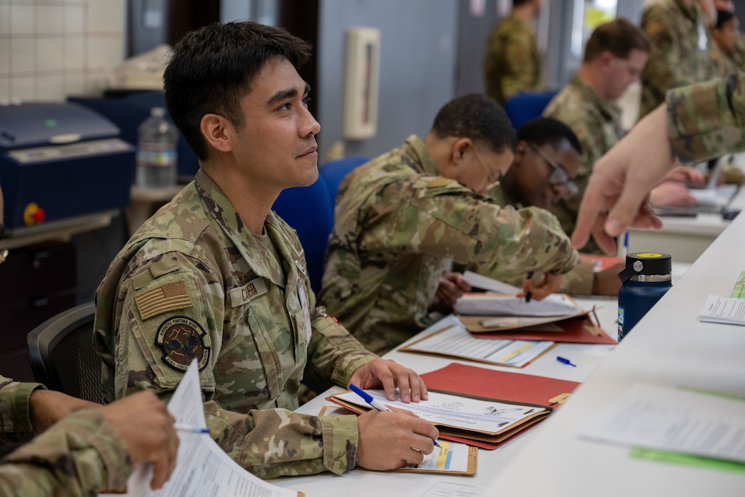A man in a military uniform checks papers in a folder.
