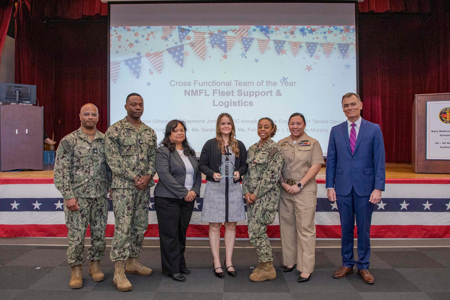 260504-N-KC192-1056 PORTSMOUTH, Va. (May 4, 2026) Sailors and staff with Naval Medical Forces Atlantic N42 Fleet Support and Logistics Team are presented the Cross-Functional Team of the Year Award by Dr. Michael McGinnis, Bureau of Medicine and Surgery (BUMED) executive director, during the 2026 Medical Logistics Symposium held on board Naval Medical Center Portsmouth, May 4, 2026. The team was recognized for driving logistics innovation and standardization, improving the delivery, accountability and readiness of medical materiel supporting deployed forces. The Navy Medicine Logistics Symposium aims to maintain a common operating picture and update the Medical Logistics community regarding the fiscal year 2026 Navy Medicine Campaign Order and the Navy MEDLOG goal to build a logistics system that delivers ready operational units to support the Naval Strategy. (U.S. Navy photo by Mass Communication Specialist Second Class Levi Decker)