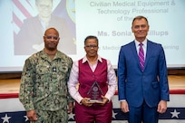 260504-N-KC192-1052 PORTSMOUTH, Va. (May 4, 2026)  Sonia Billups, with Navy Medicine Operational Training Command, is presented the Civilian Medical Equipment and Technology Professional of the Year Award by Dr. Michael McGinnis, Bureau of Medicine and Surgery (BUMED) executive director, during the 2026 Medical Logistics Symposium held on board Naval Medical Center Portsmouth, May 4, 2026. Billups was recognized for advancing property management and technical support systems, strengthening the accountability and readiness of equipment used in expeditionary operations. The Navy Medicine Logistics Symposium aims to maintain a common operating picture and update the Medical Logistics community regarding the fiscal year 2026 Navy Medicine Campaign Order and the Navy MEDLOG goal to build a logistics system that delivers ready operational units to support the Naval Strategy. (U.S. Navy photo by Mass Communication Specialist Second Class Levi Decker)