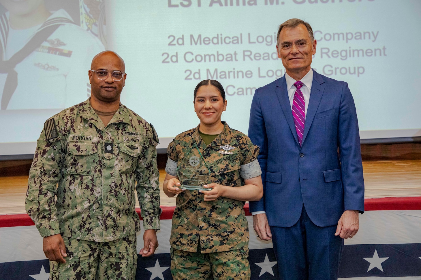260504-N-KC192-1045 PORTSMOUTH, Va. (May 4, 2026) Logistics Specialist 1st Class Alma Guerrero, center, assigned to 2nd Medical Logistics Company, is presented the Enlisted Supply Technician of the Year Award by Dr. Michael McGinnis, Bureau of Medicine and Surgery (BUMED) executive director, during the 2026 Medical Logistics Symposium held on board Naval Medical Center Portsmouth, May 4, 2026. Guerrero was recognized for delivering precise and reliable logistics support in demanding environments, ensuring deployed medical units have the supplies needed to sustain operations. The Navy Medicine Logistics Symposium aims to maintain a common operating picture and update the Medical Logistics community regarding the fiscal year 2026 Navy Medicine Campaign Order and the Navy MEDLOG goal to build a logistics system that delivers ready operational units to support the Naval Strategy. (U.S. Navy photo by Mass Communication Specialist Second Class Levi Decker)