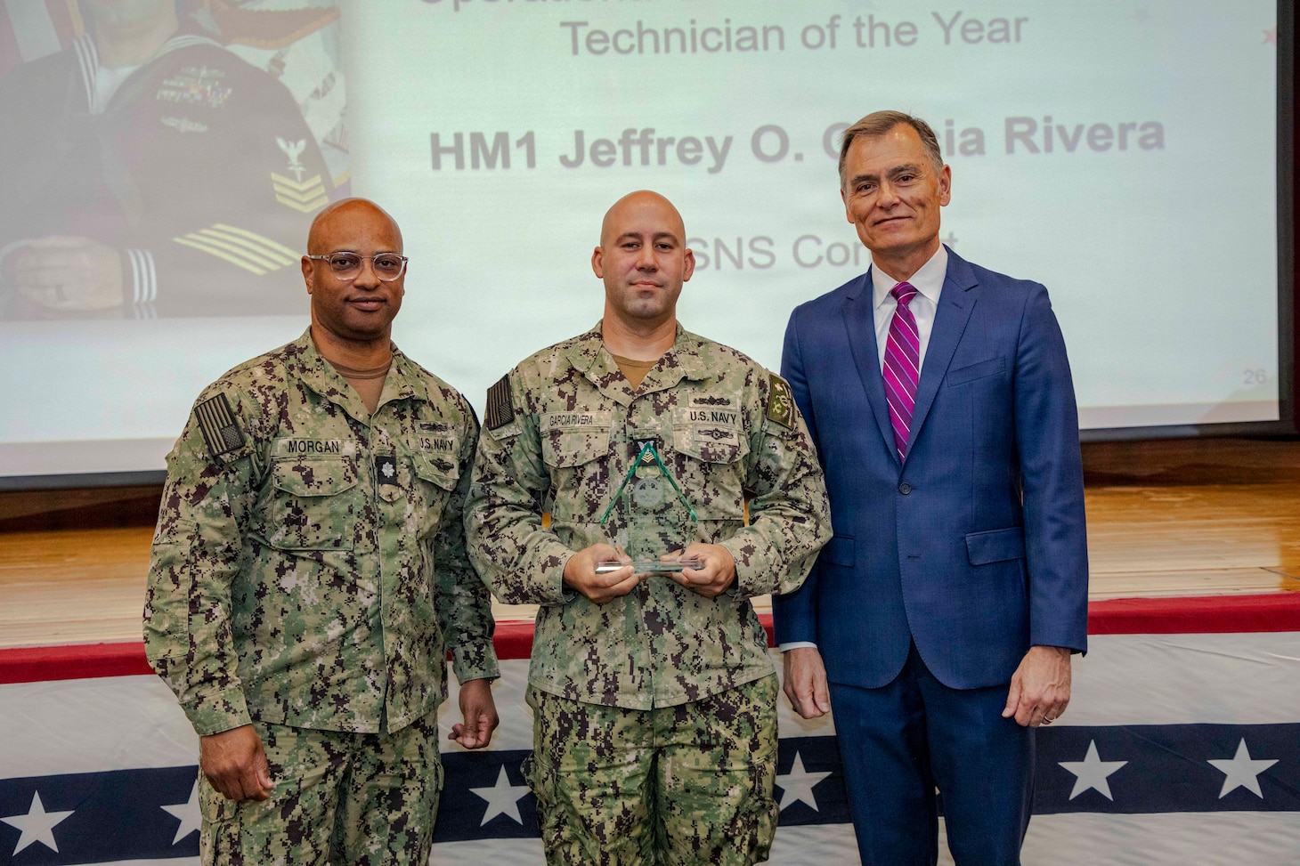 260504-N-KC192-1037 PORTSMOUTH, Va. (May 4, 2026) Hospital Corpsman 1st Class Jeffrey Garcia Rivera, assigned to Mercy-class hospital ship USNS Comfort (T-AH 20), the Operational Biomedical Equipment Technician of the Year Award by Dr. Michael McGinnis, Bureau of Medicine and Surgery (BUMED) executive director, during the 2026 Medical Logistics Symposium held on board Naval Medical Center Portsmouth, May 4, 2026. Garcia Rivera was recognized for ensuring critical medical equipment remained mission-ready in austere environments, directly supporting life-saving care and operational continuity in expeditionary settings. The Navy Medicine Logistics Symposium aims to maintain a common operating picture and update the Medical Logistics community regarding the fiscal year 2026 Navy Medicine Campaign Order and the Navy MEDLOG goal to build a logistics system that delivers ready operational units to support the Naval Strategy. (U.S. Navy photo by Mass Communication Specialist Second Class Levi Decker)