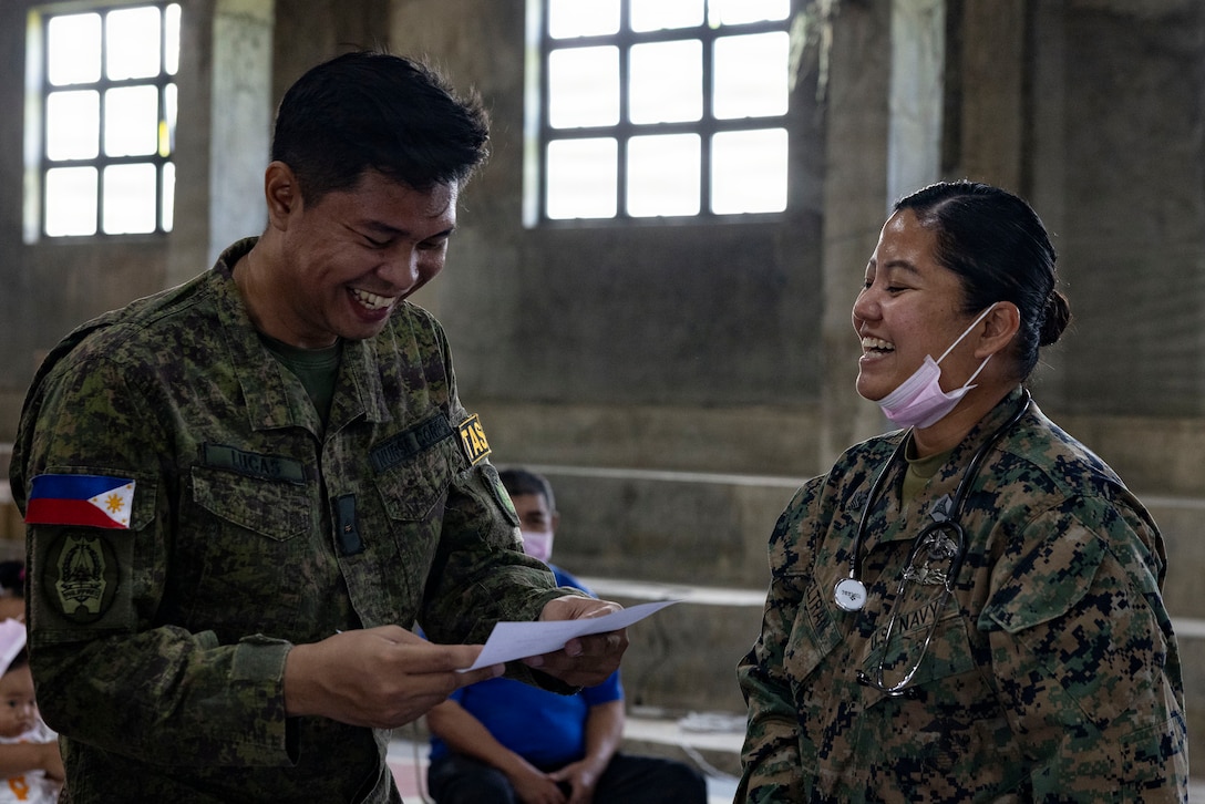 Philippine Nurse Corps 2nd Lt. Ronaldo Lucas, left, a nurse assigned to 2nd Technical Administrative Services Brigade and U.S. Navy Hospital Corpsman 1st Class Sheena Beltran, a corpsman assigned to 1st Medical Battalion, 1st Marine Logistics Group, I Marine Expeditionary Force, converse during a cooperative health engagement as part of Exercise Balikatan 2026 in San Vicente, Philippines, April 21, 2026.