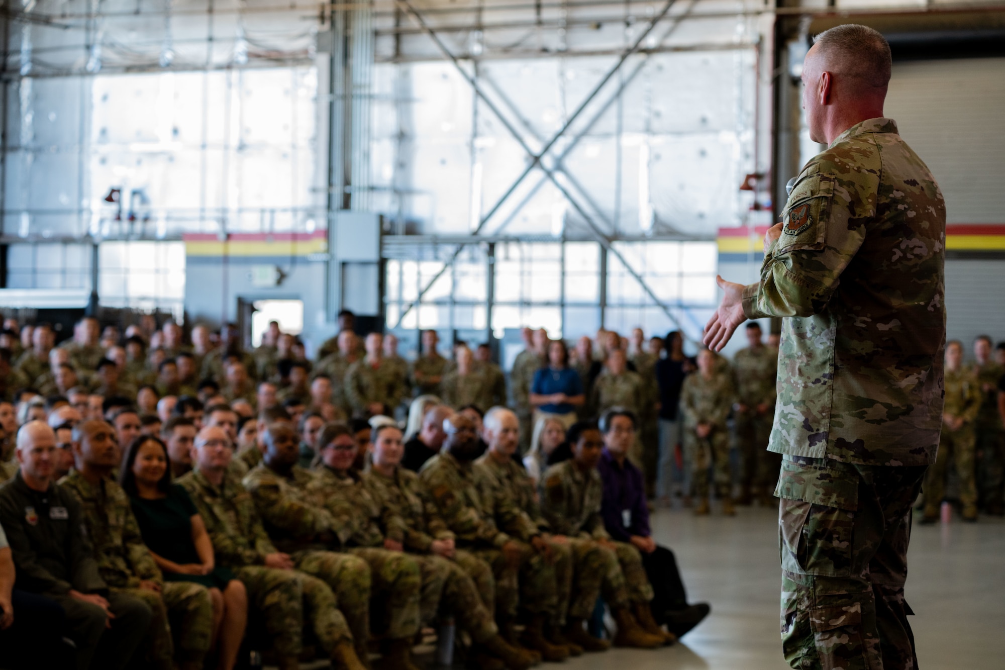 Air Force Chief Master Sergeant of the Air Force David Wolfe is seen from behind with part of his side profile visible as he addresses a seated group of Airmen during an all‑call at Hill Air Force Base.