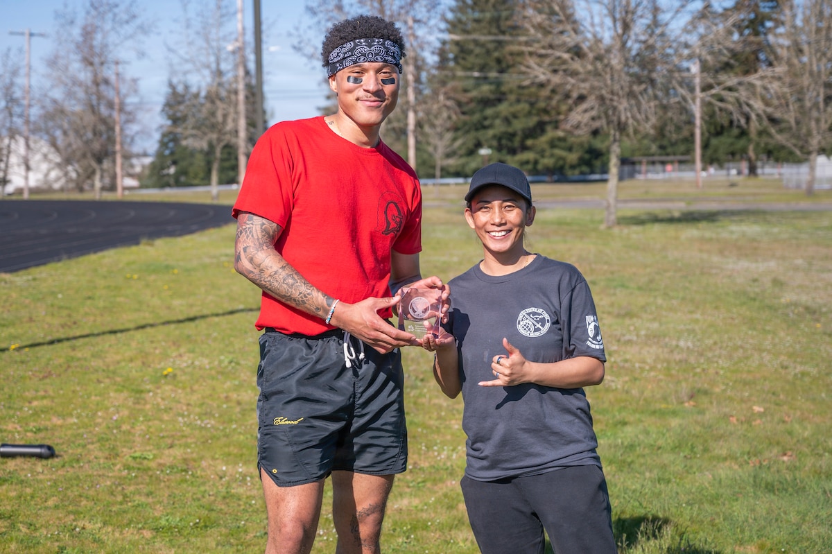 U.S. Air Force Master Sgt. Jennylyn Cabanilla, Julius A. Kolb Airman Leadership School commandant, right, presents the Commandant’s Crucible trophy to Senior Airman Thaddeus Lindsey, 627th Force Support Squadron food service shift leader, at Joint Base Lewis-McChord, Washington, April 7, 2026.