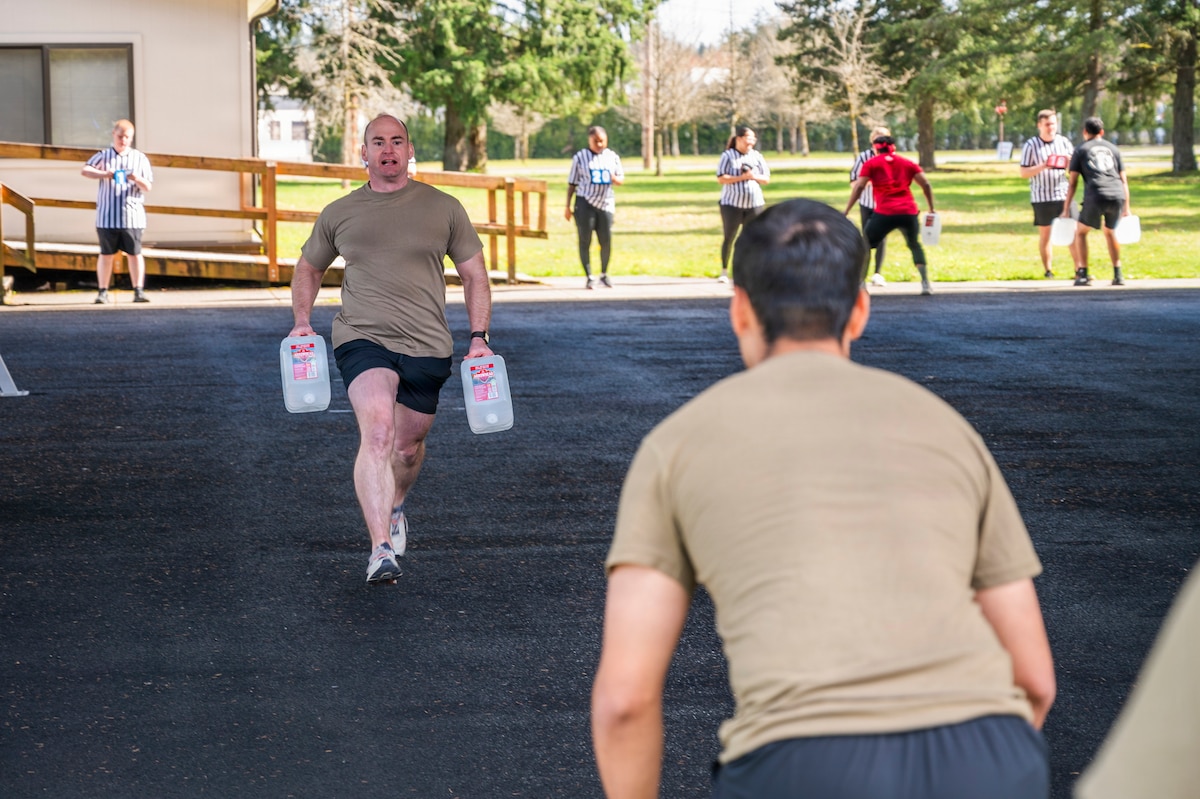 U.S. Air Force Master Sgt. Joshua Beck, 62d Maintenance Squadron aircraft structural maintenance section chief, runs water jugs back to his team during the Julius A. Kolb Airman Leadership School Commandant’s Crucible at Joint Base Lewis-McChord, Washington, April 7, 2026.