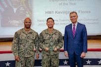 260504-N-KC192-1041 PORTSMOUTH, Va. (May 4, 2026) Hospital Corpsman 1st Class Kevinjay Flores, center, assigned to the Medical Education and Training Campus, is presented the Shore-Based Biomedical Equipment Technician of the Year Award by Dr. Michael McGinnis, Bureau of Medicine and Surgery (BUMED) executive director, during the 2026 Medical Logistics Symposium held on board Naval Medical Center Portsmouth, May 4, 2026. Flores was recognized for training the next generation of technicians, strengthening the technical readiness and reliability of equipment supporting deployed medical forces. The Navy Medicine Logistics Symposium aims to maintain a common operating picture and update the Medical Logistics community regarding the fiscal year 2026 Navy Medicine Campaign Order and the Navy MEDLOG goal to build a logistics system that delivers ready operational units to support the Naval Strategy. (U.S. Navy photo by Mass Communication Specialist Second Class Levi Decker)