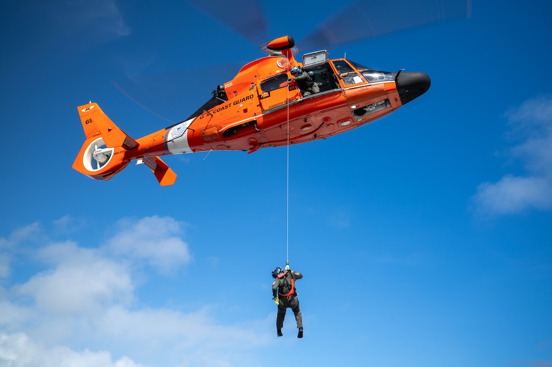 U.S. Coast Guard Petty Officer 2nd Class Kimble Petersen, an aviation survival technician assigned to Coast Guard Air Station Barbers Point in Kapolei, Hawaii, is lowered from a Coast Guard MH-65 Dolphin helicopter during a training exercise in Kaneohe Bay, Hawaii Nov. 12, 2025. Coast Guard rescue swimmers train to operate in high seas, heavy surf, and extreme weather conditions, ensuring they can respond during hurricanes, storms, and ship disasters. (U.S. Coast Guard photo by Petty Officer 2nd Class Tyler Robertson)