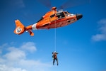 U.S. Coast Guard Petty Officer 2nd Class Kimble Petersen, an aviation survival technician assigned to Coast Guard Air Station Barbers Point in Kapolei, Hawaii, is lowered from a Coast Guard MH-65 Dolphin helicopter during a training exercise in Kaneohe Bay, Hawaii Nov. 12, 2025. Coast Guard rescue swimmers train to operate in high seas, heavy surf, and extreme weather conditions, ensuring they can respond during hurricanes, storms, and ship disasters. (U.S. Coast Guard photo by Petty Officer 2nd Class Tyler Robertson)