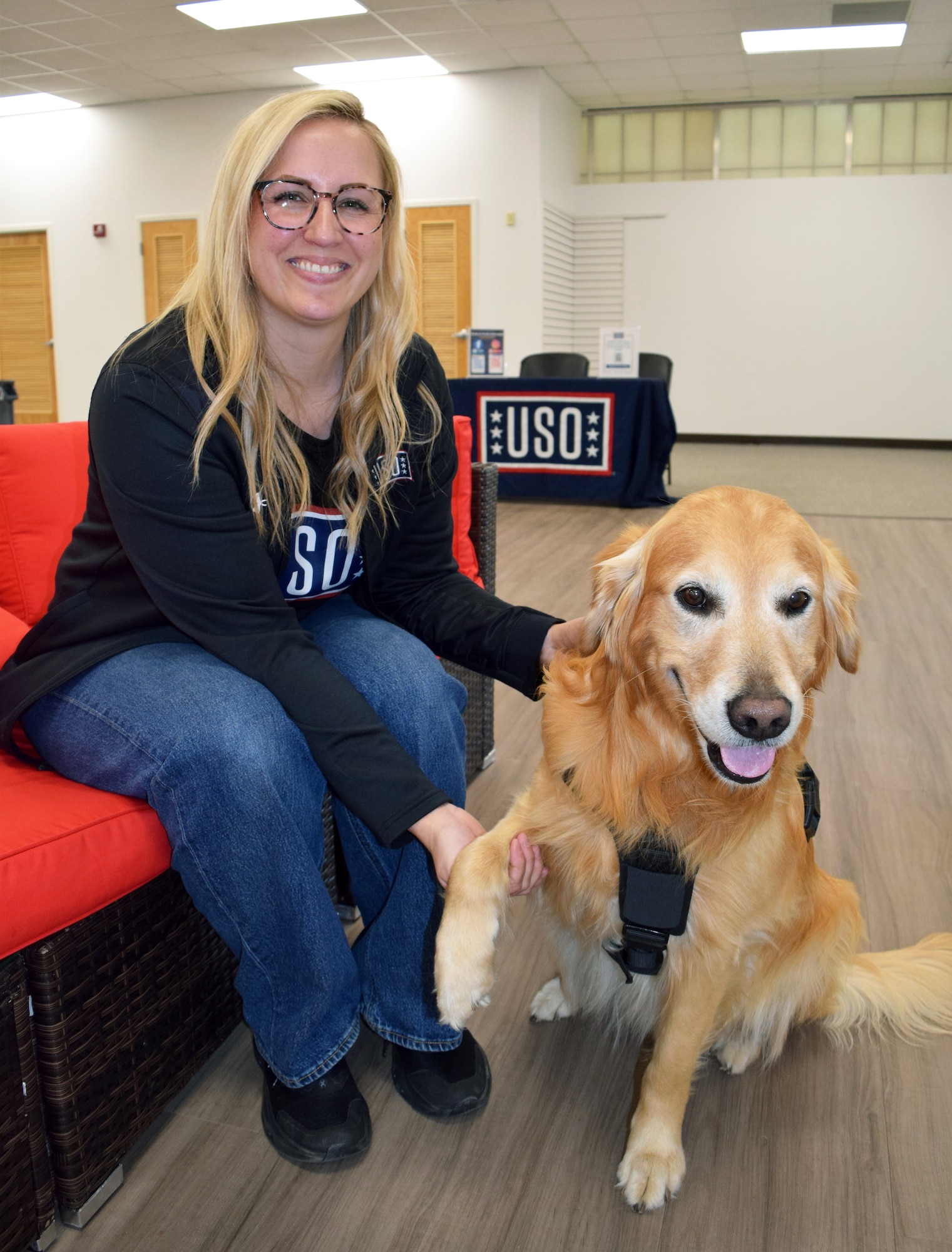 Cari Matthews, area operations manager for USO New Jersey and Delaware, receives a paw from Ranger, a therapy dog, at the new USO center at Joint Base McGuire-Dix-Lakehurst, N.J., April 23, 2026. Ranger, recently named the USO North Region’s 2026 Canine of the Year, helps welcome service members as they partake in USO programs and activities. (U.S. Air Force photo by Kris Patterson)